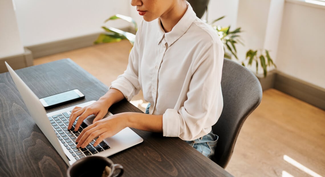 Home office scene: woman with laptop, hinting at shifts in NYC's office market dynamics.