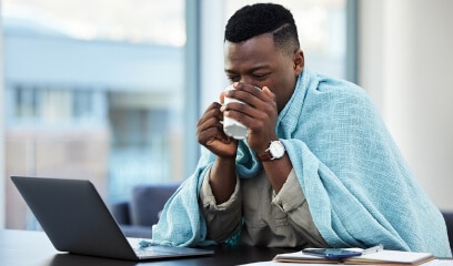 Young businessman in NYC office battles cold, adjusting to frigid air while working