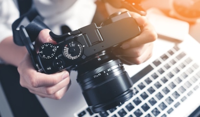 Photographer at desk editing photos on laptop for commercial real estate listings in NYC.