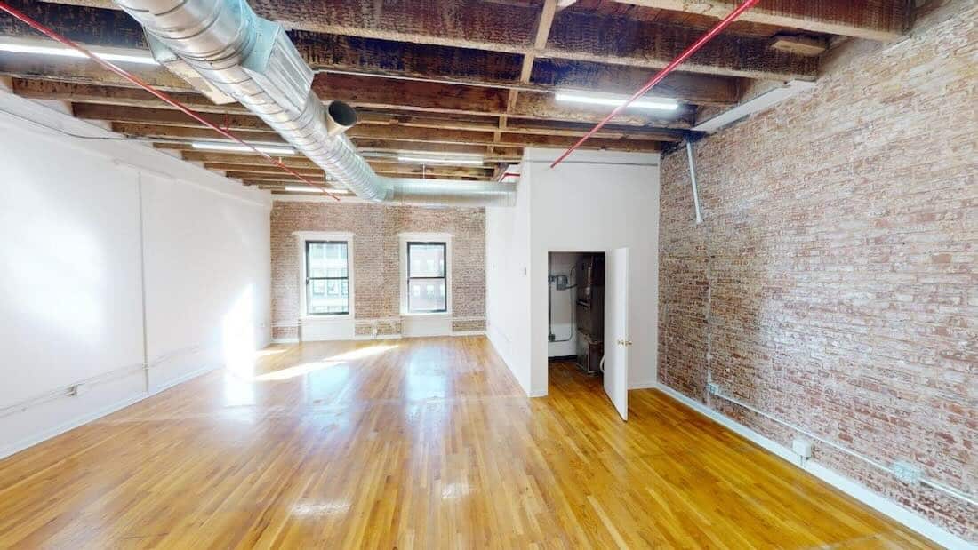 Suite #509: Spacious, sunlit room with polished wood floors and brick walls.