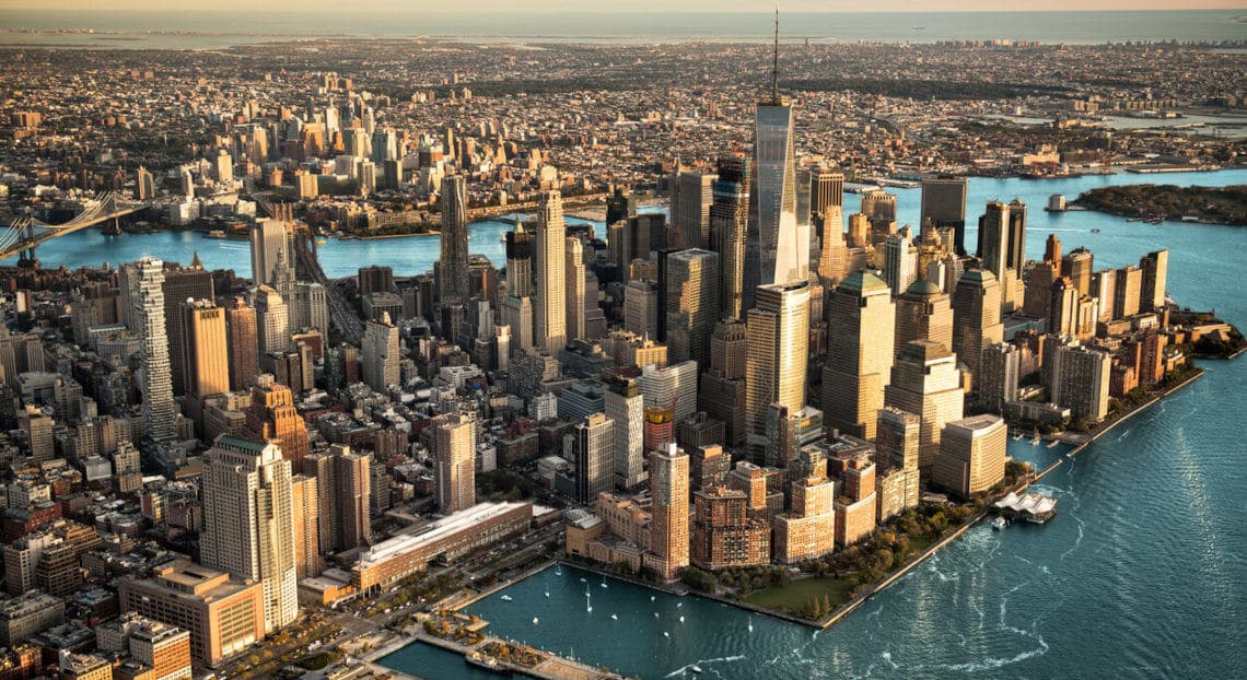 Aerial view of NYC at sunset, showcasing the city's iconic landmarks & it's vast urban landscape